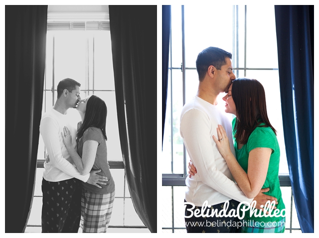 engageded couple kissing in front of a windo