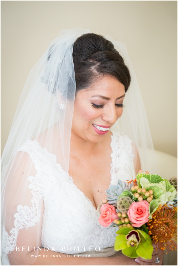 a bride admires her bouquet of pink and green succulents and roses
