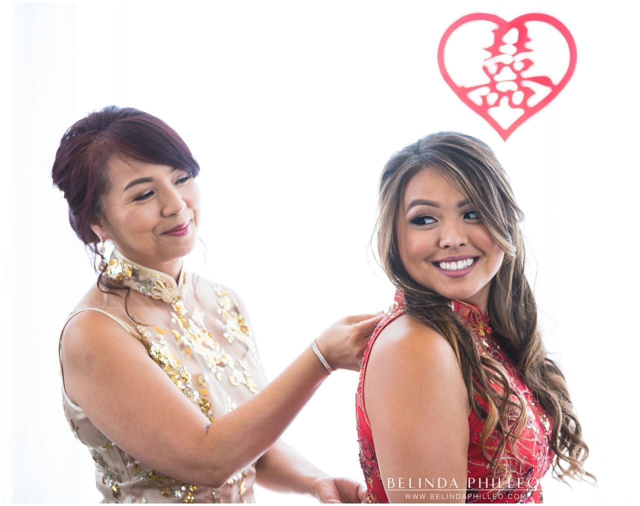 Mother of the bride zips up bride's qipao before the tea ceremony