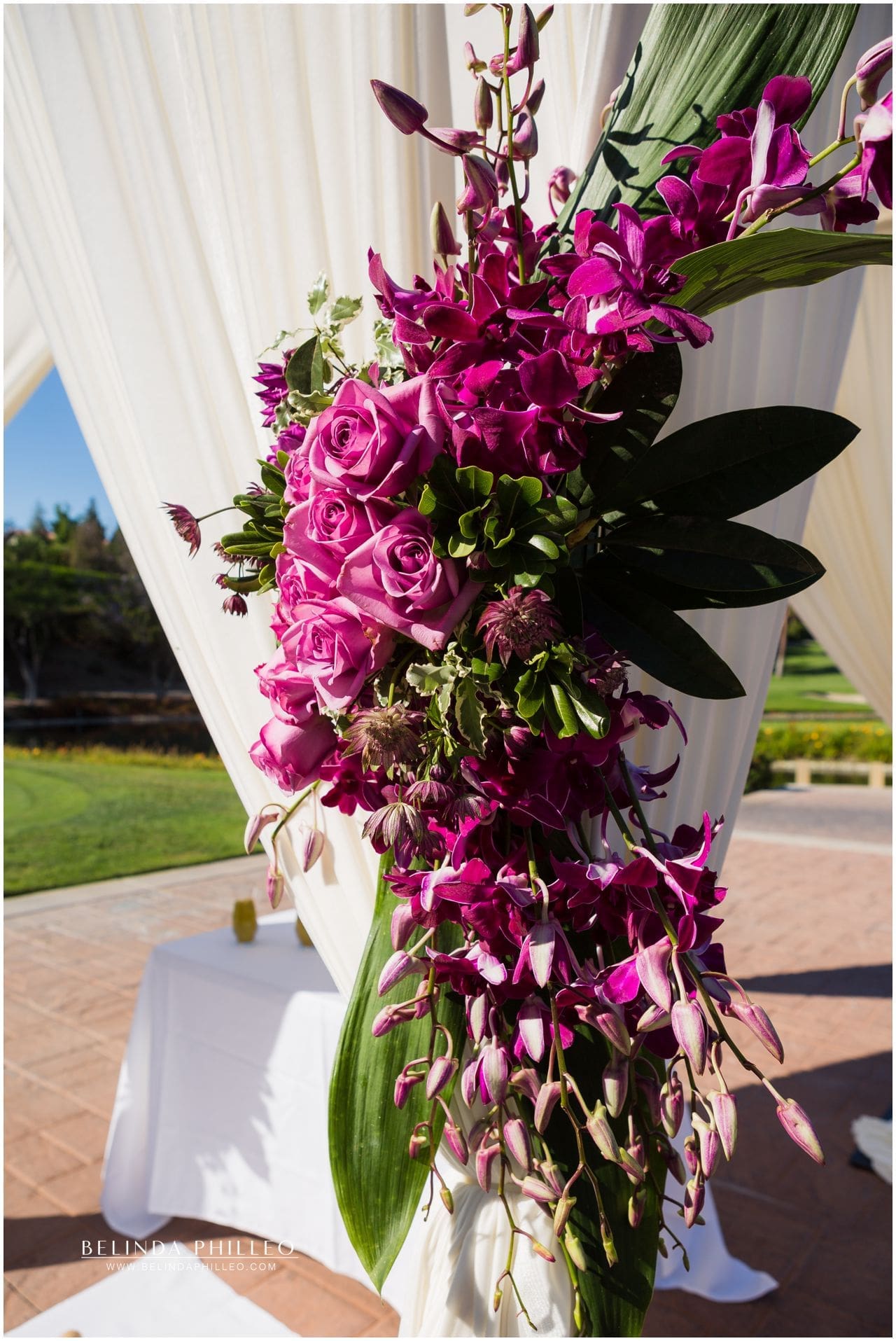 Purple and fuscia roses and orchids decorate wedding ceremony at Friendly Hills Country Club, Whittier, CA