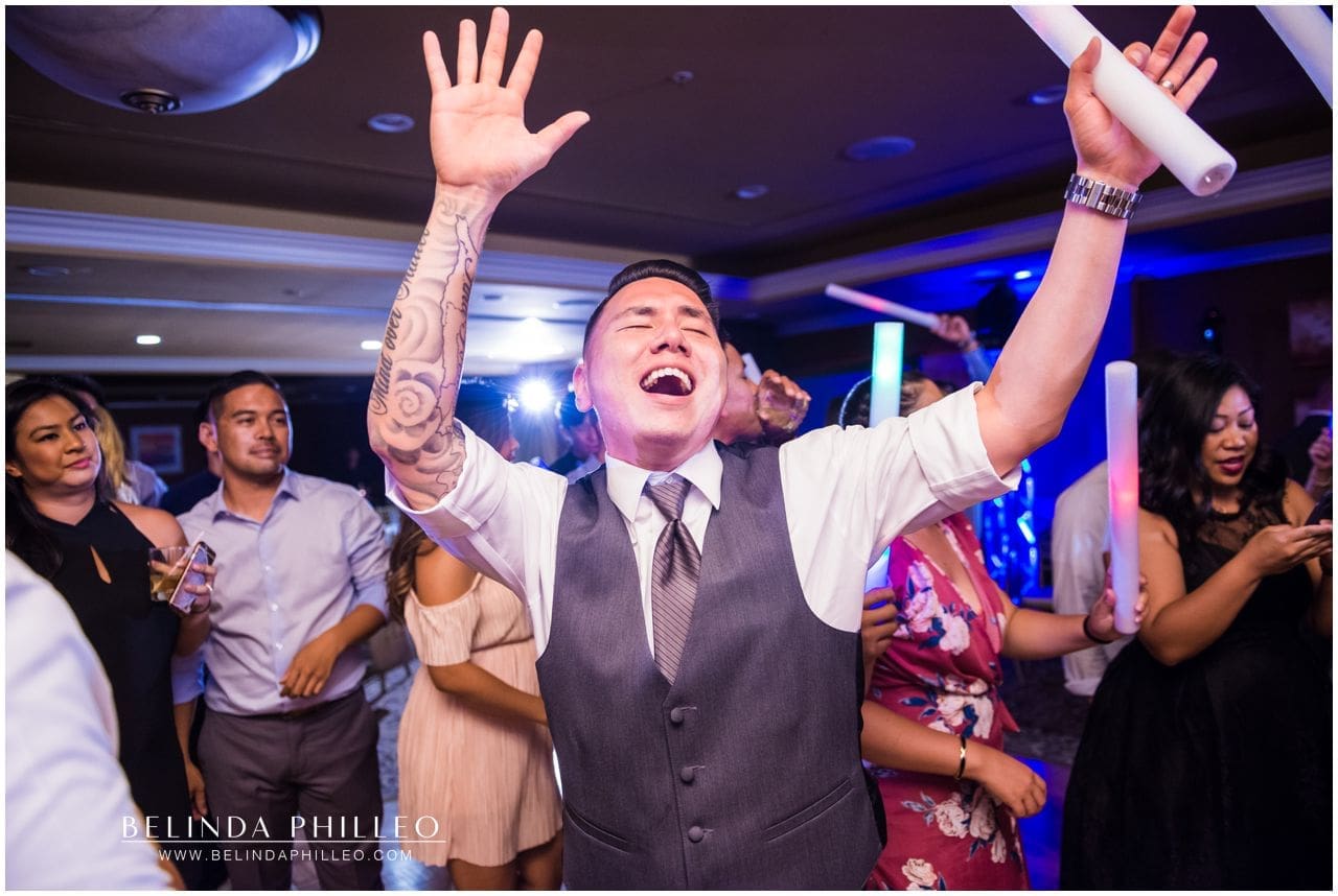 Groom dances gleefully with a glowstick at his Friendly Hills Country Club wedding reception