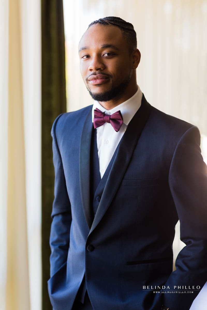 Groom models navy tux and merlot bowtie from Friar Tux