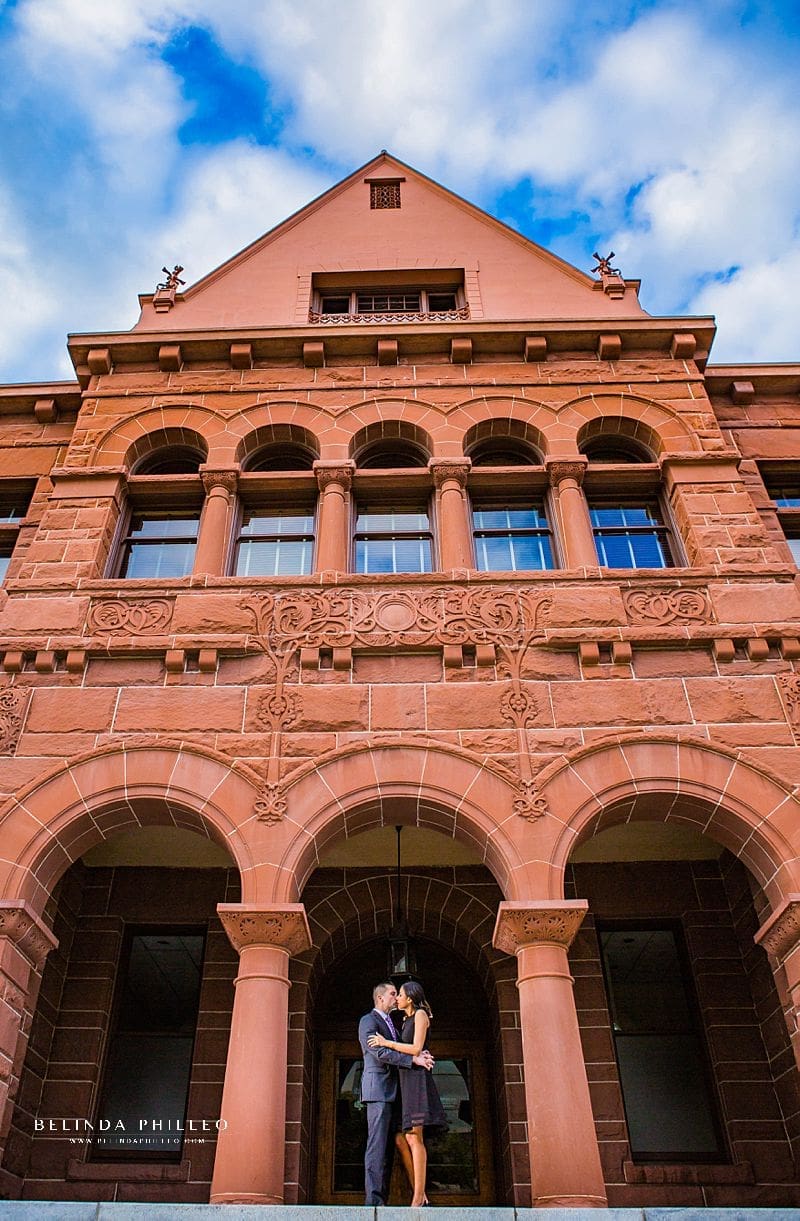 Engagement Session Locations in Orange County. A couple stops for a kiss on the front steps of the Historic Orange County Courthouse in Downtown Santa Ana, CA