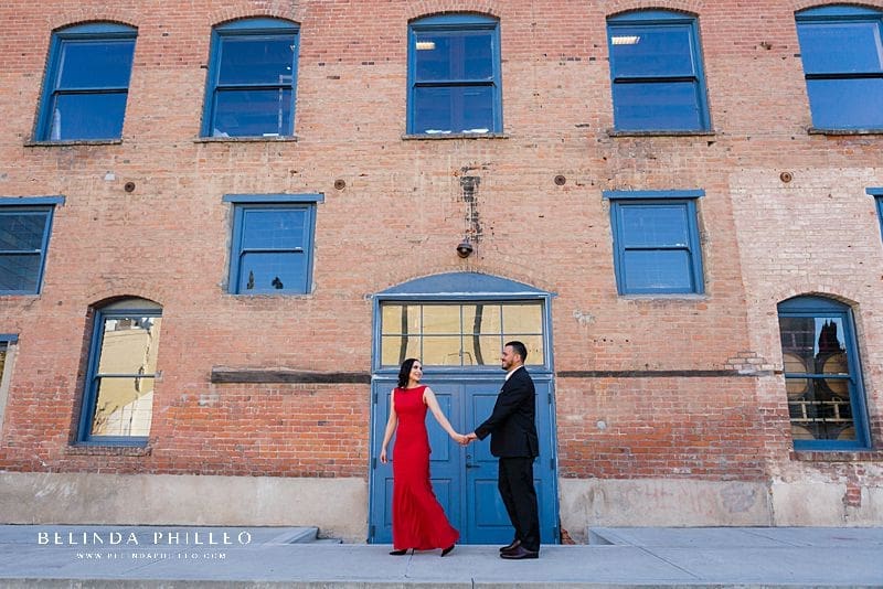 Engagement locations in Orange County, CA. A couple in formal attire poses for a photo in an alleyway in Downtown Santa Ana during their engagement session.
