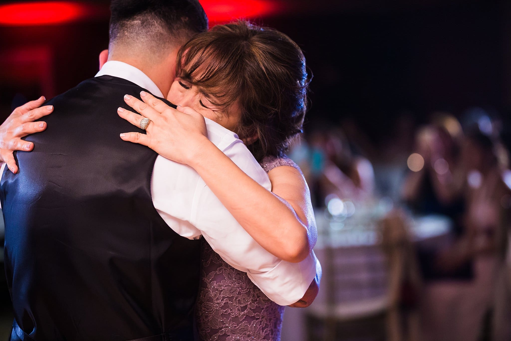 Emotional wedding photos. Mother of the groom cries on son's shoulder during the mother-son dance.