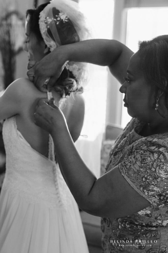 Bride's mother helps her adjust the straps on her Justin Alexander wedding gown