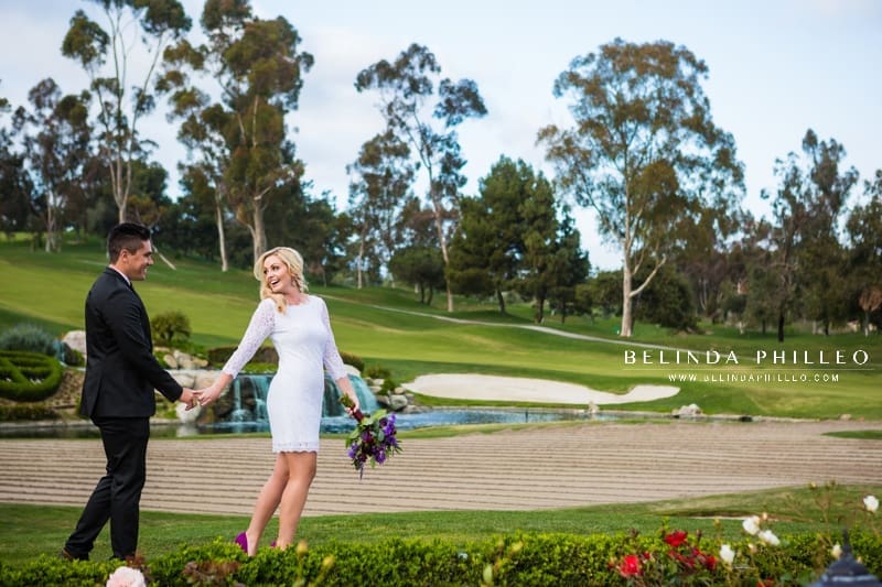 Bride and groom walking around the golf course at Marbella Country Club, enjoying the view of the waterfall at at one of Orange County's best outdoor wedding venues. 