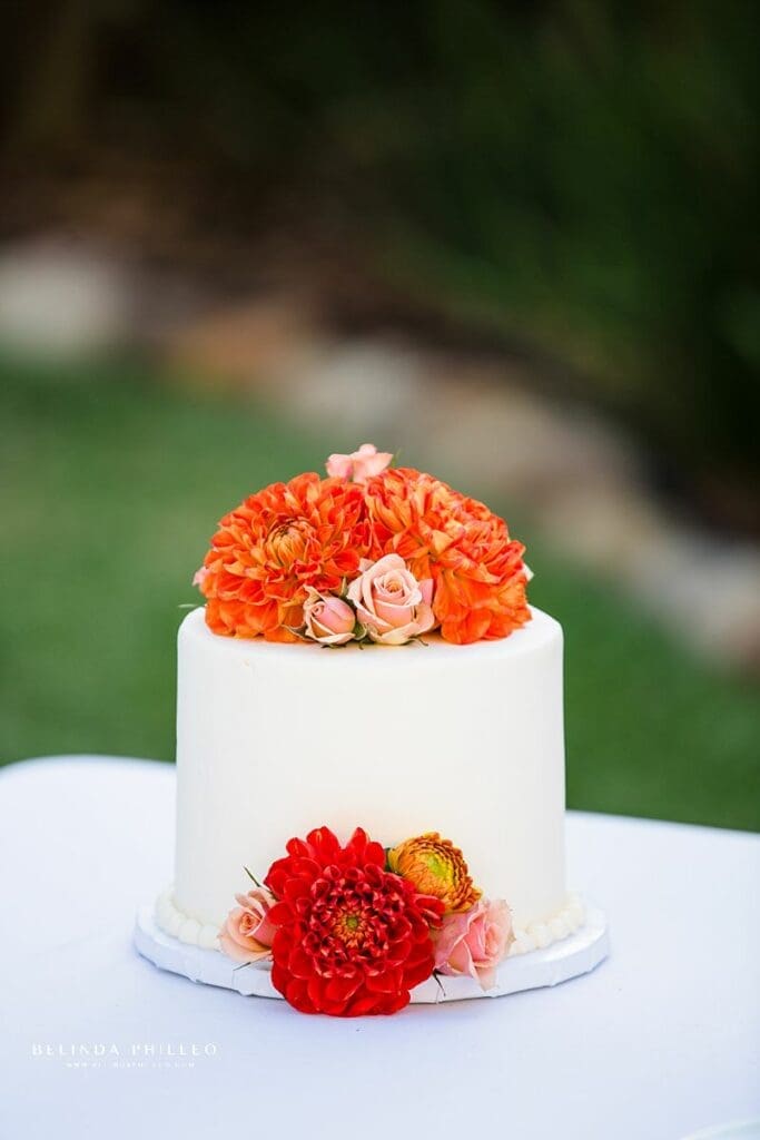 Simple one tier vegan wedding cake with orange and pink florals