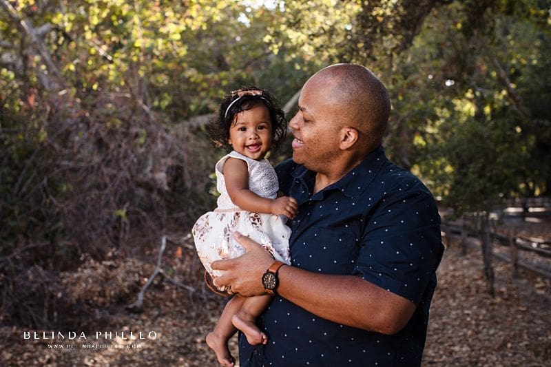 Irvine Regional Park Family portraits - father admires his beautiful baby girl while she smiles for a portrait