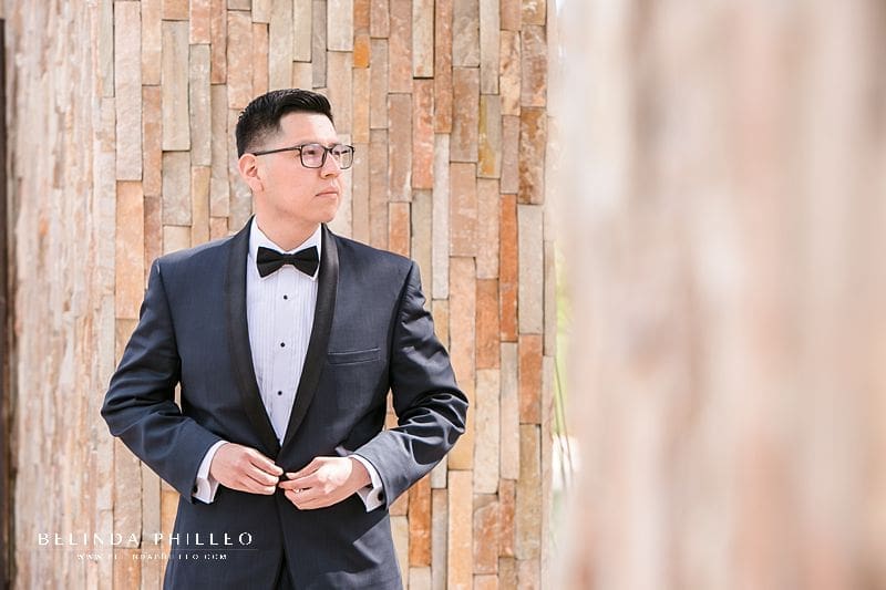 Southern California wedding photographer Belinda Philleo shares her best posing tips for men. A groom buttons his tuxedo jacket before heading down the aisle to get married.