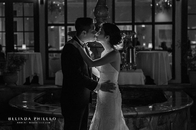 Newlyweds share a kiss in front of the fountain outside Summit House wedding reception