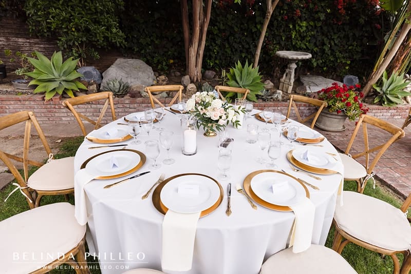 Closeup of wedding reception table with flowers and gold cutlerly