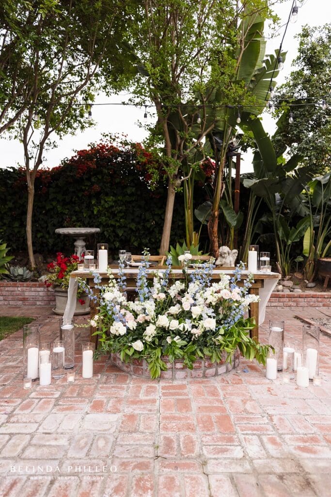 Sweetheart table decorated with flowers and candles at a backyard wedding