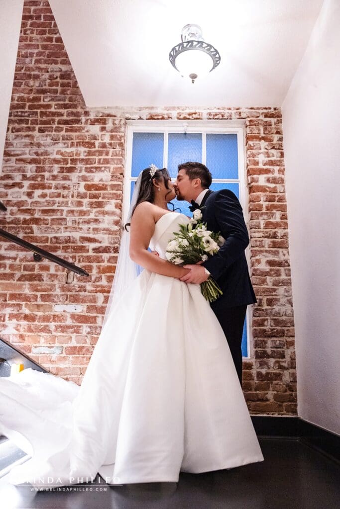 bride and groom share a kiss at the top of a stairwell