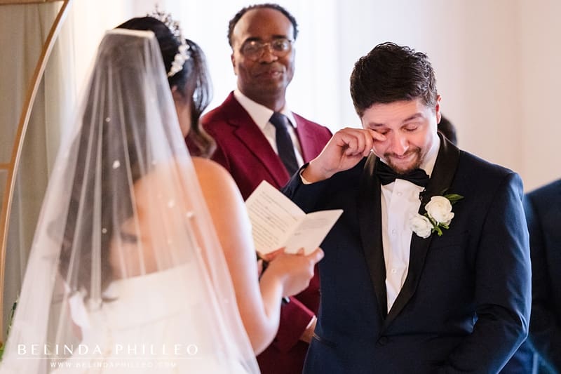 Groom wipes away a tear as the bride reads her vows