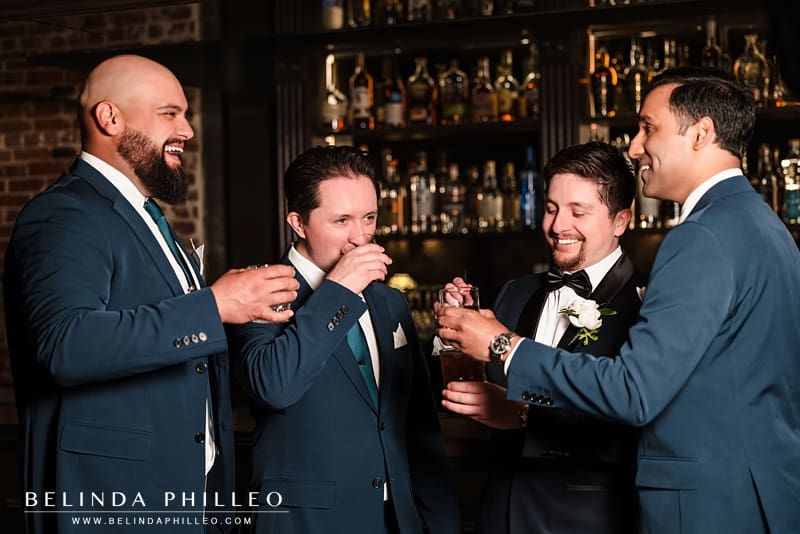 A groom and his groomsmen toast and cheers at the bar