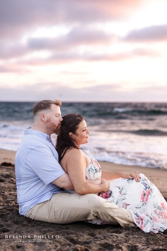 Engaged couple enjoys watching the sunset on the beach
